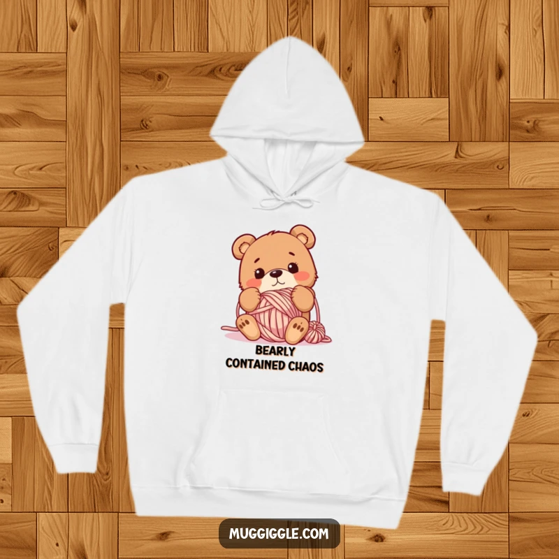 Funny hoodie showcasing a bewildered bear utterly tangled in a large ball of yarn, embodying cozy chaos and whimsical charm.