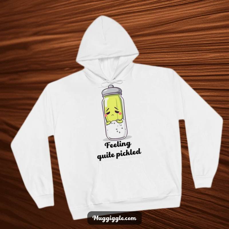Funny and anxious pickle character hiding behind a salt shaker, featured on a cozy hoodie.